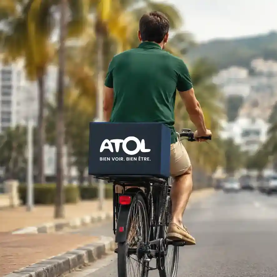 photo d'un homme de dos sur un vélo avec un carton Atol derrière lui en ville.