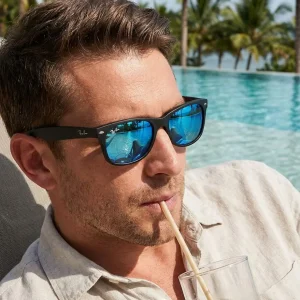 photo d'une paire de lunette RayBan New Wayfarer noire portée par un homme devant une piscine à Nouméa.
